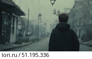 A solitary young individual walks along a quiet street shrouded in fog, evoking a sense of mystery and introspection amidst the urban environment. Стоковое AI-видео, аниматор Данила Большаков / Фотобанк Лори