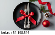 Christmas plate with fork and knife under red bow surrounded by Christmas attributes on white background. And. Copy space. AI generative. Стоковое AI-изображение, AI-художник Роман Дзюбало / Фотобанк Лори