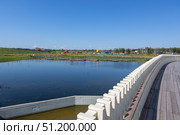 Magnitogorsk, Russian Federation - August 24, 2025: Urban resort attraction featuring serene water landscape, vibrant playgrounds, and modern architectural design with copy space for promotional use. Редакционное фото, фотограф Ирина Ручушкина / Фотобанк Лори