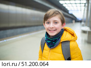 Улыбающийся 11-летний школьник на станции метро, ​​ожидающий прибытия поезда. Стоковое фото, фотограф Яна Проничева / Фотобанк Лори