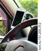 A phone is mounted on the steering wheel of a car.  Russia. Moscow. 24.08.25. Стоковое фото, фотограф Ярославский Максим / Фотобанк Лори