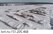 aerial photography of unloading logs from a car trailer using a manipulator and storing logs in an open area in winter. Стоковое видео, видеограф Алексей Сергеев / Фотобанк Лори