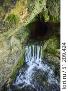 Wild cave outside. The river flows out of the cave, a waterfall. Speleology and surveys. Стоковое фото, фотограф Наталия Кирсанова / Фотобанк Лори