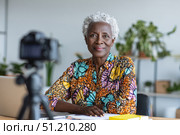 Elegant elderly black woman in colorful attire posing with confidence indoors. Стоковое AI-изображение, AI-художник Евгения Пархоменко / Фотобанк Лори