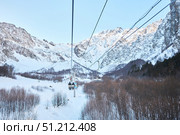 Cei, Russia. - January 06, 2024: A ski lift is visible against the background of a snow-covered mountain. The ski lift is surrounded by trees and snow. Редакционное фото, фотограф Наталия Кирсанова / Фотобанк Лори