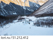 Cei, Russia. - January 06, 2024: A ski lift is visible against the background of a snow-covered mountain. The ski lift is surrounded by trees and snow. Редакционное фото, фотограф Наталия Кирсанова / Фотобанк Лори
