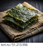 Stacked Nori Seaweed Sheets on a Rustic Burlap Napkin. Generative AI. Стоковое AI-изображение, AI-художник Roman Zavorotny / Фотобанк Лори