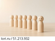 A Group of Wooden Figurines with One Smiling Character Promoting Positivity and Individuality Amongst Uniformity. Стоковое AI-изображение, AI-художник Башкирова Анна / Фотобанк Лори
