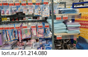 A store rack with a variety of office supplies and school supplies. The upper rows contain sets of decorative stickers with images of animals, erasers, correction tapes, pens with figured holders. The middle level contains sets of colored pens, pencils, rulers, markers and stickers. The lower part contains notebooks, notepads and organizers with bright designs. On the right, folders and ring binders in blue and purple tones are stacked in piles. All products are provided with price tags with promotional offers. The atmosphere of the photo conveys the diversity of school and office stationery in a supermarket. Редакционное фото, фотограф Анна Кривицкая / Фотобанк Лори