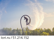Flyboarding activity in a scenic outdoor location during sunset with a flyboard athlete soaring above the water. Acrobatics on a flyboard, somersaults and splashes. Стоковое фото, фотограф Владимир Разгуляев / Фотобанк Лори
