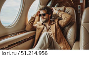 A man enjoys a relaxing moment inside a private jet, showcasing his stylish outfit and sunglasses while gazing out at the scenery. Стоковое AI-видео, аниматор Данила Большаков / Фотобанк Лори