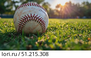 A well-worn baseball sits on lush green grass as the sun sets, creating a warm glow in the local park. Стоковое AI-видео, аниматор Данила Большаков / Фотобанк Лори