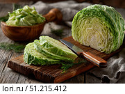 Organic freshly white cabbage on rustic table surface. Green fresh cabbage. Partially sliced raw shredded cabbage and a half on a wooden cutting board with a knife. Preparation of vegetables salad. Стоковое AI-изображение, AI-художник Марина Демидюк / Фотобанк Лори