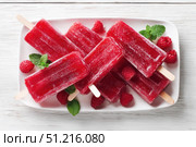 Berry juice popsicles in a plate on a white wooden table with fresh berries. Bright Ice pops with mint leaves and raspberries. Gut-health red pink berry popsicles. Inviting summer scene. Frozen treats. Стоковое AI-изображение, AI-художник Марина Демидюк / Фотобанк Лори