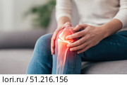 Knee pain icon. Joint pain, Arthritis and tendon problems. Woman in jeans sitting sofa, touching nee at pain point. Mature person feeling unwell, suffering from pain in leg. Red effect painful injury. Стоковое AI-изображение, AI-художник Марина Демидюк / Фотобанк Лори