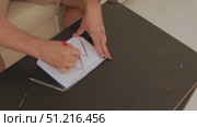 Man drawing zigzag lines on notepad with red pencil. Стоковое видео, видеограф Константин Шишкин / Фотобанк Лори