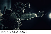 Modern soldier in combat uniform, helmet and radio headset, shooting handgun in the darkness. Oleg Zabielin / Stocktrek Images/TASS. Стоковое фото, агентство ТАСС / Фотобанк Лори