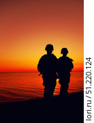 Silhouette of two soldiers patrolling a coastline at sunset. Oleg Zabielin / Stocktrek Images/TASS. Стоковое фото, агентство ТАСС / Фотобанк Лори