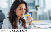 Professional female professional drinking lemon infused water while working on laptop, staying hydrated during busy workday in modern corporate workspace. Стоковое AI-изображение, AI-художник Юрий Поздников / Фотобанк Лори