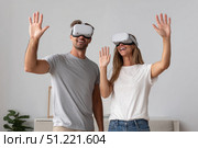 Couple wearing vr headsets, experiencing immersive digital landscape, waving and smiling during synchronized virtual interaction, sharing technological excitement. Стоковое AI-изображение, AI-художник Юрий Поздников / Фотобанк Лори