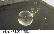 Sunlight streaming through large soap bubble, surrounded by smaller bubbles, creating iridescent display against blurred urban background, showcasing delicate fragility. Стоковое AI-видео, аниматор Юрий Поздников / Фотобанк Лори