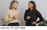 Two diverse women in casual attire sharing laughter, drinking water and engaging in friendly conversation with genuine connection. Стоковое AI-видео, аниматор Юрий Поздников / Фотобанк Лори