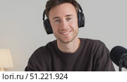 Digital media professional recording podcast, wearing noise canceling headphones, smiling confidently in home studio workspace, representing contemporary freelance content creation. Стоковое AI-видео, аниматор Юрий Поздников / Фотобанк Лори