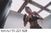 Powerful female athlete practicing boxing punches on a heavy bag, showcasing her strength, skill, and determination in a modern gym setting, illuminated by bright lights. Стоковое AI-видео, аниматор Юрий Поздников / Фотобанк Лори