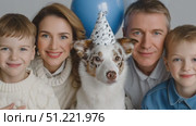 Happy family wearing party hats, celebrating birthday with twin boys and australian shepherd dog, standing together against neutral gray backdrop. Стоковое AI-видео, аниматор Юрий Поздников / Фотобанк Лори