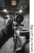 First person view of a soldier wearing gloves aiming an assault rifle equipped with a red dot sight, firing a shot at a target in an indoor shooting range. Стоковое AI-видео, аниматор Юрий Поздников / Фотобанк Лори