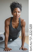 Muscular woman practicing upward facing dog pose, curly hair flowing, gray tank top stretching on minimalist yoga mat indoors. Стоковое AI-видео, аниматор Юрий Поздников / Фотобанк Лори