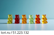 Gummy bears isolated on pastel blue surface, evenly spaced, minimalist style. Стоковое AI-изображение, AI-художник ALLA YURTAYEVA / Фотобанк Лори