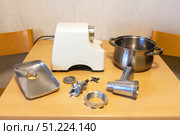 Components of an electric meat grinder before assembling and chopping products. Tray, knife, auger, mesh, fastening screw on a kitchen table. Modern kitchen mechanisms. Top view, close-up, copy space. Стоковое фото, фотограф Виктория Катьянова / Фотобанк Лори