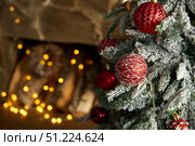 Christmas toys balls hang on fir branch, against backdrop of fireplace. Стоковое фото, фотограф Aleksandra Selivanova / Фотобанк Лори