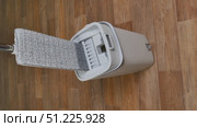Modern mop is wrung out from water in gray bucket for washing floors on brown floor, cleaning concept household chores. Стоковое видео, видеограф Катерина Белякина / Фотобанк Лори