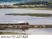 An old Soviet L-series steam locomotive. The Ruskeala Express retro train is driving along the lake. Side view from above. Russia, Republic of Karelia, Sortavala, August 11, 2025. Редакционное фото, фотограф Photojuli / Фотобанк Лори