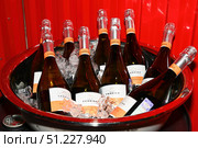 Vladivostok, Russia, 20 August 2025 - Bottles of Rocca Cerrina Prosecco wine on ice in a large metal bucket against a red background at festive event. Редакционное фото, фотограф Татьяна Терехина / Фотобанк Лори