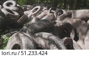 A large pile of old tires accumulates in a wooded location, posing environmental risks. Debris surrounds the area, showing the impact of improper waste disposal on nature. Стоковое видео, видеограф Громов Александр / Фотобанк Лори