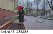 A child is joyfully playing with a colorful umbrella during a rainy weather, enjoying the moment. Стоковое видео, видеограф Olesia Kondrateva / Фотобанк Лори