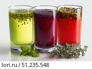 Glasses of tea with different types and colors infused with herbs, on a white background. The teas are green, black, red, purple, and yellow oolong, with loose leaf tea leaves with mint and lavender. Стоковое AI-изображение, AI-художник Марина Демидюк / Фотобанк Лори