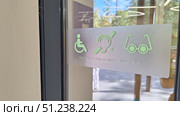 Accessible entrance with disability symbols on glass door in sunlit building. Стоковое фото, фотограф Zakharova Natasha / Фотобанк Лори