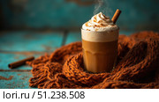 Steaming pumpkin spice latte with whipped cream and cinnamon stick on cozy autumn background. Стоковое фото, фотограф David Kashakhi / Фотобанк Лори