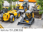 JCB telehandler, skid steer, and wheel loader parked in urban lot. London, UK, 14 July 2024. Редакционное фото, фотограф Zydrius Tartenis / Фотобанк Лори