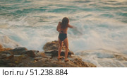 Woman dancing with graceful arm movements on rocky shore at golden hour. Стоковое видео, видеограф Igor Tichonow / Фотобанк Лори