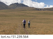 Two climbers go to the mountains through a green meadow. Стоковое фото, фотограф Михаил Яковлев / Фотобанк Лори