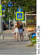 Two women walking down a sidewalk next to a bike rack.  Russia. Moscow. 24.08.25. Редакционное фото, фотограф Ярославский Максим / Фотобанк Лори