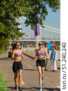 Two women running on a sidewalk with a crowd of people watching.  Russia. Moscow. 24.08.25. Редакционное фото, фотограф Ярославский Максим / Фотобанк Лори