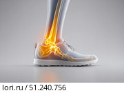 Leg with ankle joint pain icon. Foot wearing running shoes showing the bones in the ankle area. Grey floor. Feet with red effect of painful injury problems. Legs with anatomical detail glowing orange. Стоковое AI-изображение, AI-художник Марина Демидюк / Фотобанк Лори