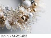 Delicate wreath of golden Christmas decorations hangs on the white wall. Magic and joy festive celebrations during the winter season. Elegant gold and silver Ornaments beautifully decorated setting. Стоковое AI-изображение, AI-художник Марина Демидюк / Фотобанк Лори