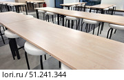 Empty classroom with wooden desks and white chairs in modern educational setting. Стоковое фото, фотограф Zakharova Natasha / Фотобанк Лори